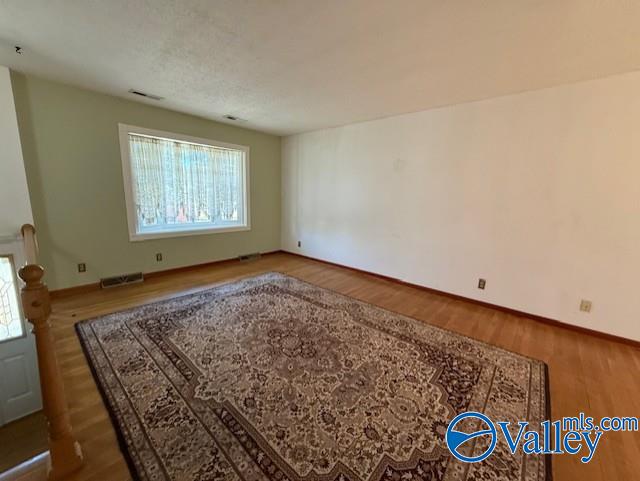 spare room with wood finished floors, visible vents, and baseboards