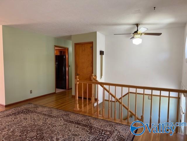 empty room with a ceiling fan, baseboards, and wood finished floors