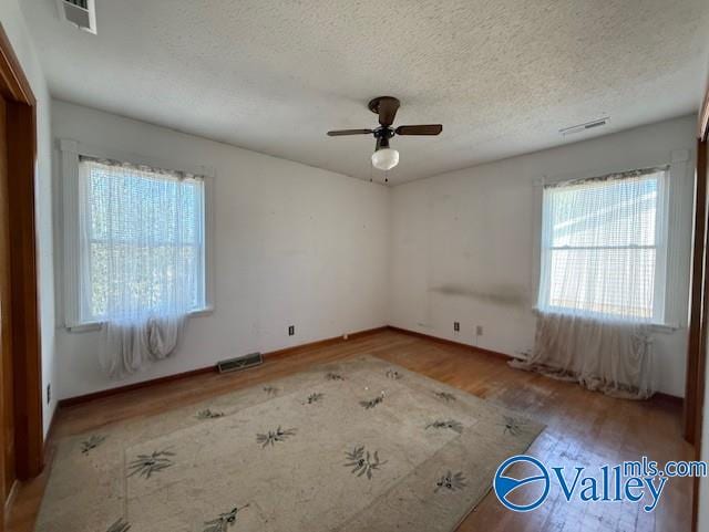 spare room featuring visible vents, a textured ceiling, and wood finished floors