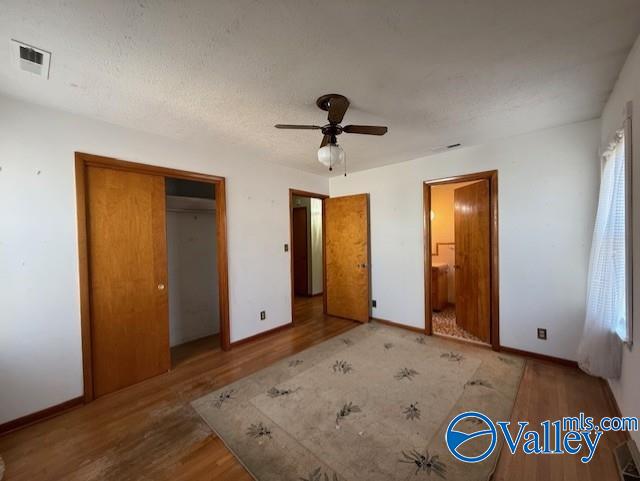 unfurnished bedroom with baseboards, visible vents, ceiling fan, wood finished floors, and a closet