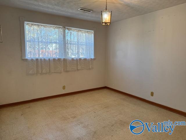 unfurnished room with light floors, baseboards, visible vents, and a textured ceiling