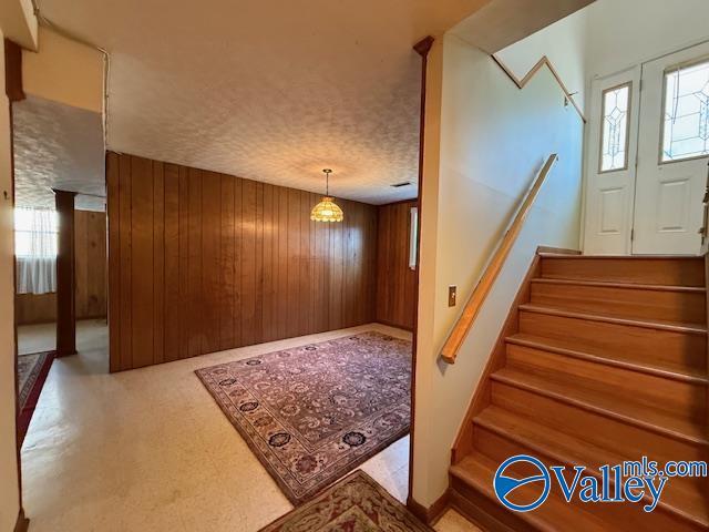 staircase featuring wood walls and a textured ceiling