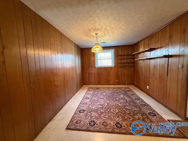 unfurnished dining area with a textured ceiling, wooden walls, and light colored carpet