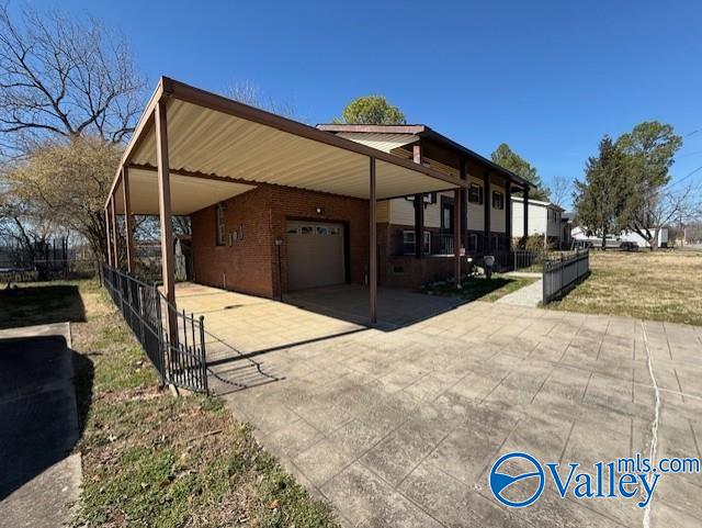 view of home's exterior featuring an attached garage, driveway, fence, and a carport