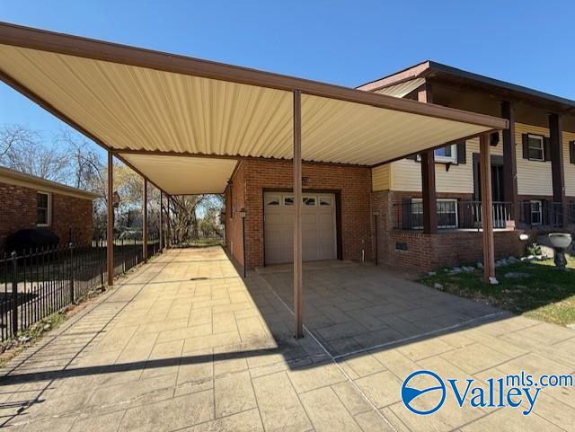 exterior space featuring a garage, a carport, concrete driveway, and fence