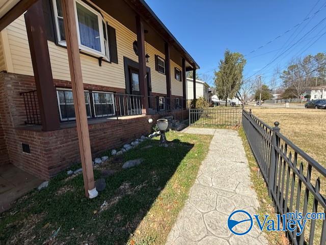 view of property exterior featuring brick siding, crawl space, and fence