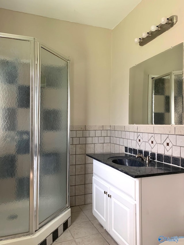 bathroom featuring tile patterned floors, vanity, an enclosed shower, and tile walls