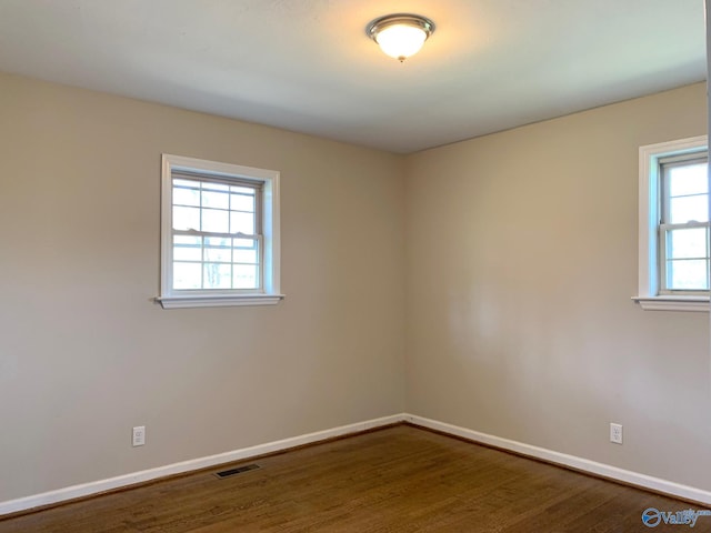 spare room featuring wood-type flooring and plenty of natural light