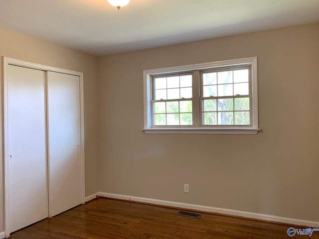 unfurnished bedroom with dark hardwood / wood-style flooring and a closet