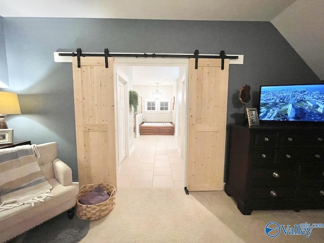 interior space with light tile patterned floors, a barn door, and vaulted ceiling