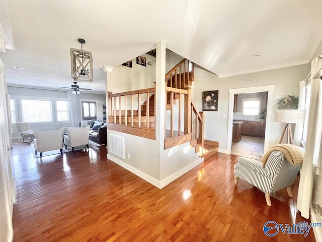 stairway featuring ceiling fan, ornamental molding, and wood-type flooring