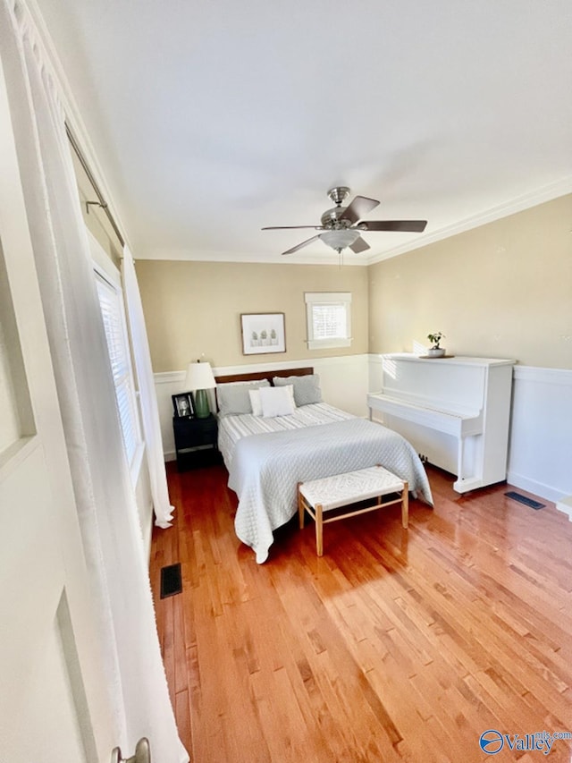 bedroom with ceiling fan, ornamental molding, and wood-type flooring