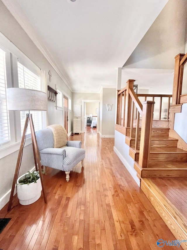 sitting room with plenty of natural light, ornamental molding, and wood-type flooring