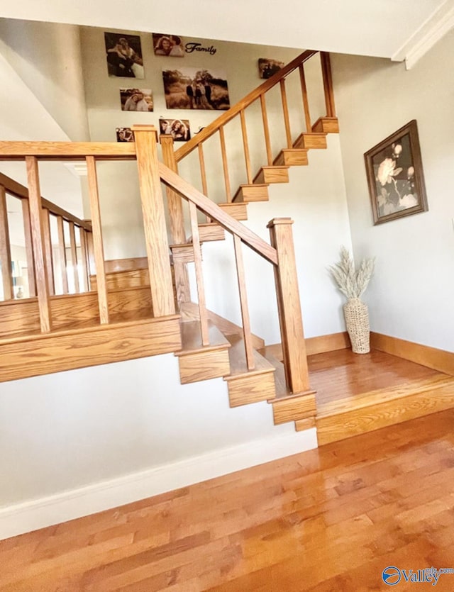 stairway featuring wood-type flooring and crown molding