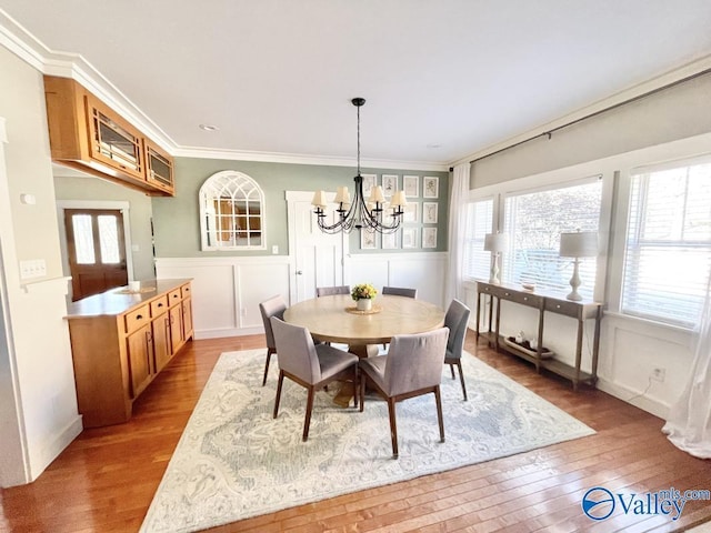 dining room featuring light hardwood / wood-style floors, crown molding, and a notable chandelier