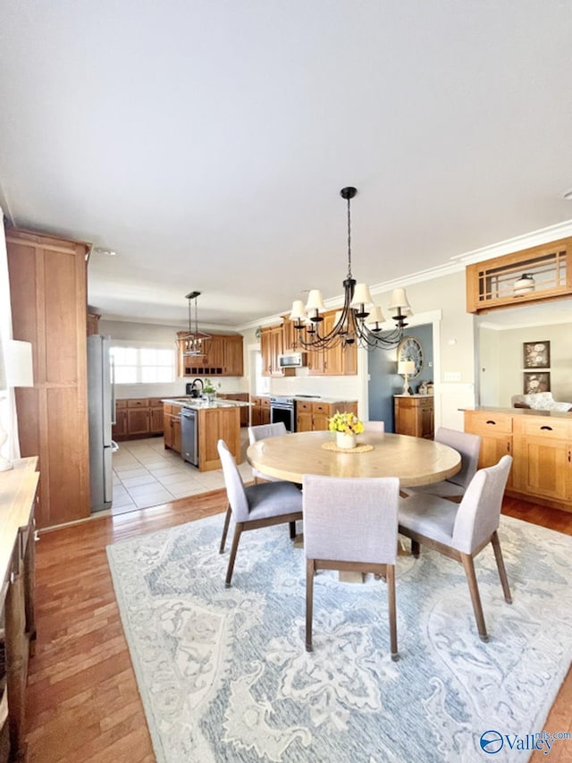 dining area with light hardwood / wood-style floors, crown molding, and a notable chandelier