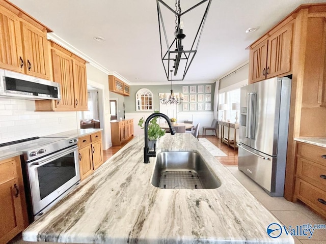 kitchen with backsplash, pendant lighting, sink, an island with sink, and stainless steel appliances