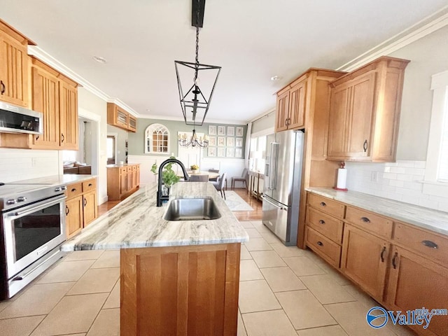 kitchen featuring tasteful backsplash, sink, hanging light fixtures, appliances with stainless steel finishes, and an island with sink