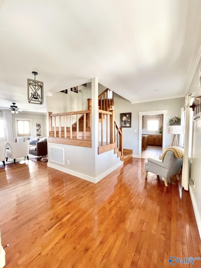 unfurnished living room with ceiling fan, hardwood / wood-style floors, and crown molding