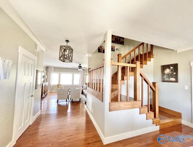 stairway featuring ceiling fan, ornamental molding, and hardwood / wood-style floors