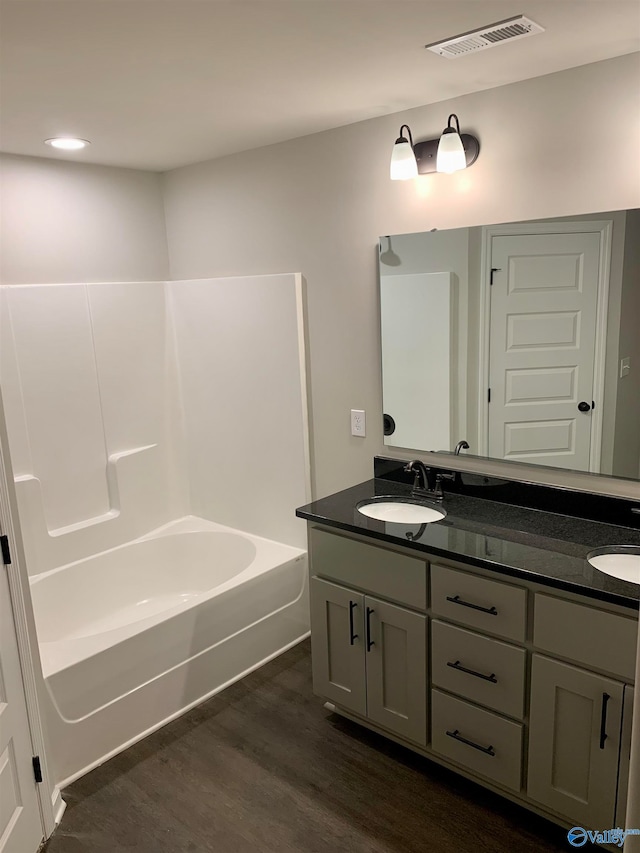 bathroom with double vanity, shower / bathing tub combination, and hardwood / wood-style floors