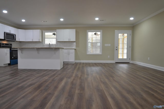 kitchen with a kitchen island, white cabinetry, a kitchen bar, stainless steel appliances, and crown molding