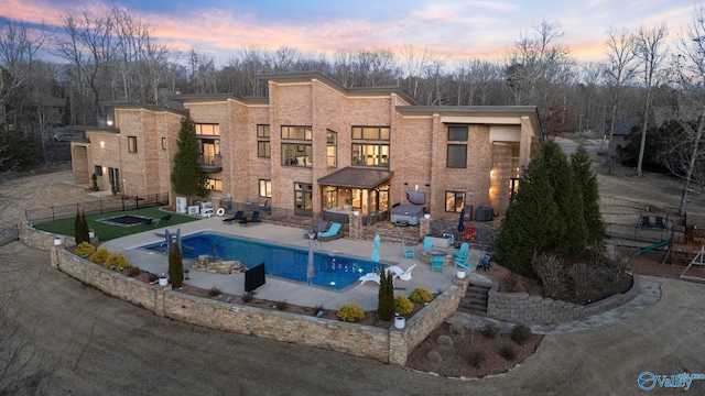 pool at dusk featuring a patio, fence, and a fenced in pool