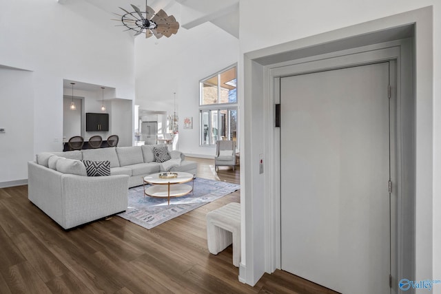 living room with an inviting chandelier, a towering ceiling, and dark wood-style flooring