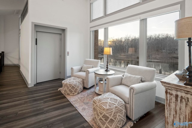 sitting room with dark wood-type flooring, baseboards, and a towering ceiling