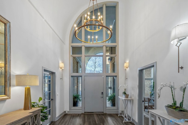 foyer featuring a chandelier, wood finished floors, baseboards, and a towering ceiling