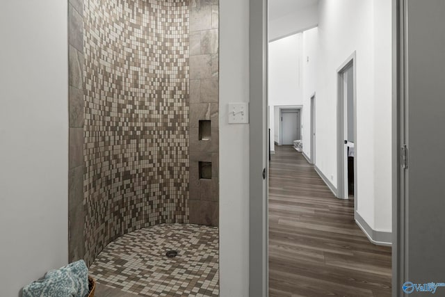 bathroom featuring wood finished floors, baseboards, and tiled shower