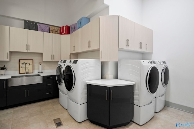 washroom with a sink, baseboards, visible vents, and washer and clothes dryer