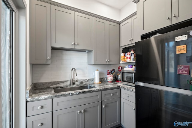 kitchen featuring a sink, stainless steel appliances, backsplash, and gray cabinets