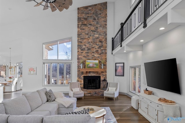 living area with an inviting chandelier, a fireplace, a towering ceiling, and dark wood-style flooring