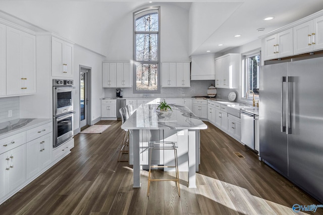 kitchen featuring white cabinetry, dark wood-type flooring, a high ceiling, and stainless steel appliances