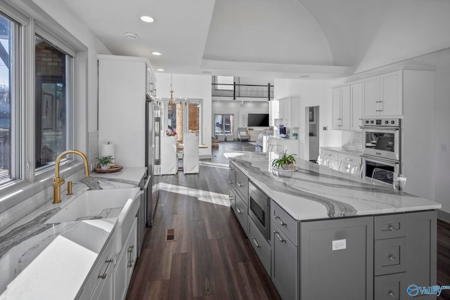 kitchen with dark wood finished floors, gray cabinets, appliances with stainless steel finishes, white cabinetry, and a sink