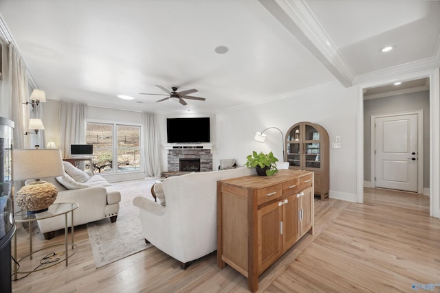 living room with a stone fireplace, ornamental molding, light hardwood / wood-style floors, and ceiling fan