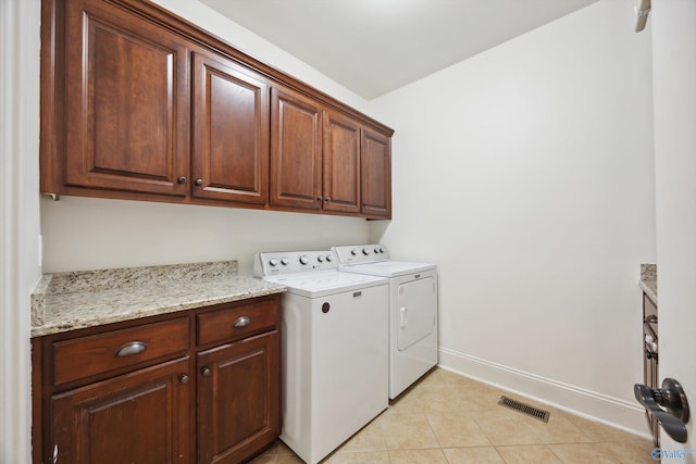 laundry area featuring light tile patterned floors, washing machine and dryer, and cabinets