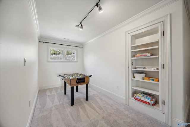 recreation room with ornamental molding, light colored carpet, track lighting, and built in features