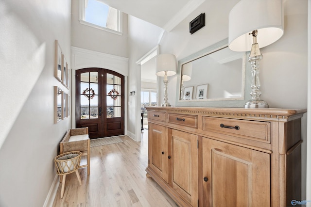 foyer entrance featuring french doors, crown molding, and light wood-type flooring