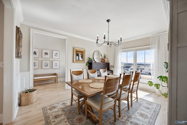 dining area with ornamental molding, light hardwood / wood-style flooring, and a notable chandelier