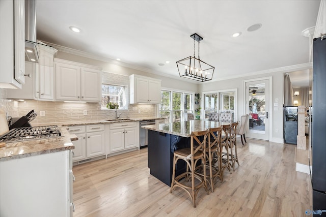 kitchen with dishwasher, light stone countertops, white cabinets, a kitchen island, and decorative light fixtures