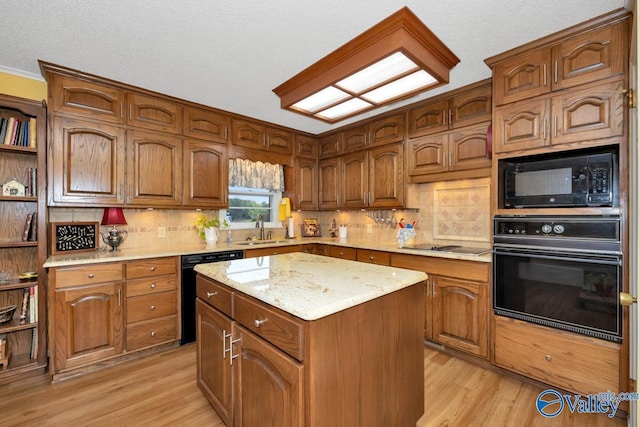 kitchen with sink, backsplash, black appliances, a kitchen island, and light wood-type flooring