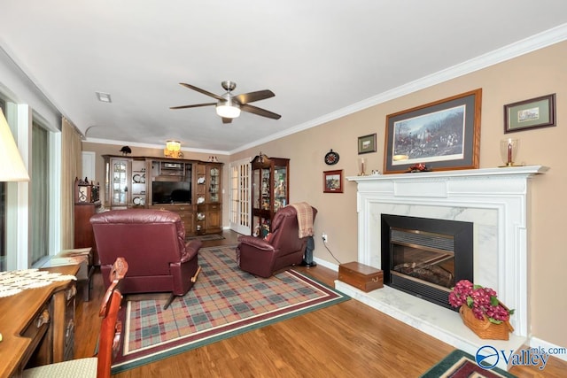 living room with crown molding, ceiling fan, a fireplace, and hardwood / wood-style floors