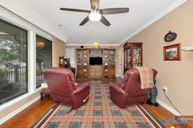 living room with wood-type flooring, ornamental molding, and ceiling fan