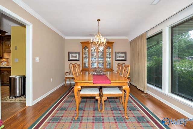 dining space with an inviting chandelier, ornamental molding, and dark hardwood / wood-style floors