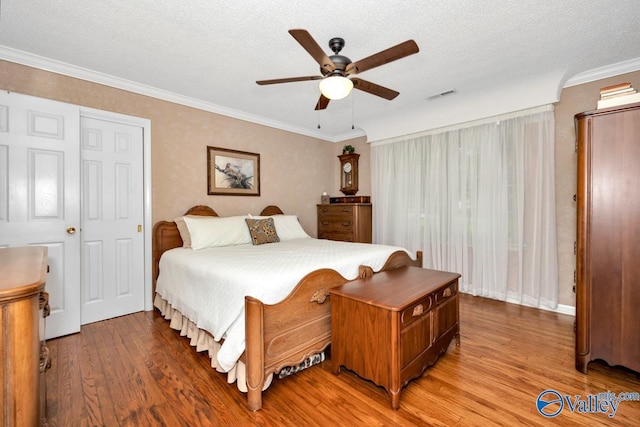 bedroom with hardwood / wood-style flooring, ornamental molding, ceiling fan, and a textured ceiling