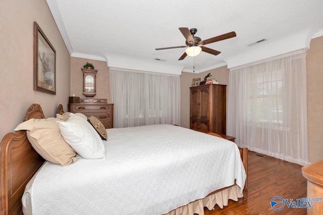 bedroom featuring crown molding, ceiling fan, dark hardwood / wood-style floors, and a textured ceiling