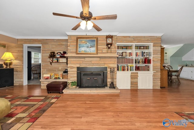 living room with wood-type flooring, ornamental molding, and ceiling fan