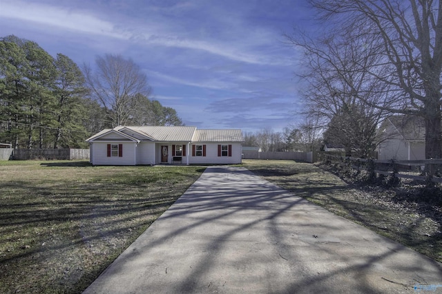 ranch-style home with metal roof, a front lawn, fence, and driveway